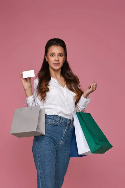 Sonriente joven mujer sosteniendo bolsa de paquete y tarjeta bancaria de crédito —  Fotos de Stock
