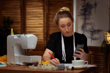 Dikiş makinesi üzerinde çalışan genç ve güzel terzi.