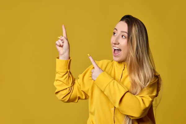Jonge vrouw wijzend weg op gele achtergrond — Stockfoto