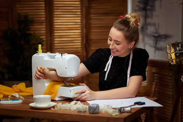 Vacker ung sömmerska som arbetar med symaskin — Stockfoto