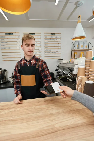 Красивый бариста принимает оплату с кредитной карты через автомат в кафе. — стоковое фото