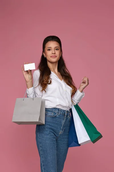 Sonriente joven mujer sosteniendo bolsa de paquete y tarjeta bancaria de crédito —  Fotos de Stock