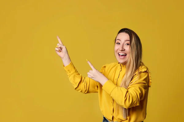 Giovane donna che indica via su sfondo giallo — Foto Stock