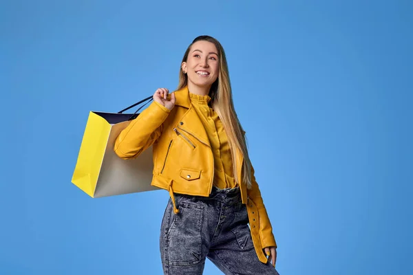 Vrouw in lederen jas holding boodschappentas met aankopen — Stockfoto