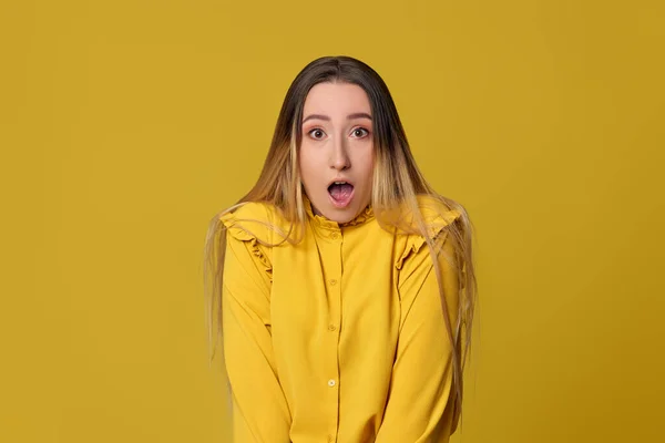 Überraschte blonde Frau auf gelbem Hintergrund. Menschliche Emotionen — Stockfoto