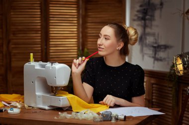 Dikiş makinesi üzerinde çalışan genç ve güzel terzi.