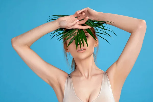 Blonde woman hiding behind palm tropical leaves — Fotografie, imagine de stoc