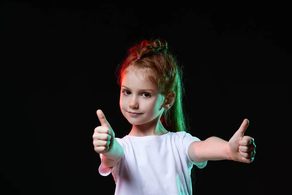 Kind meisje tonen OK gebaar op zwarte achtergrond. — Stockfoto