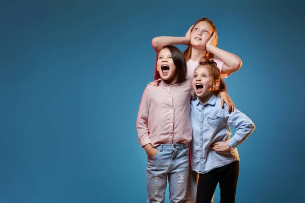 Drie kids meisjes staan samen op blauwe achtergrond — Stockfoto