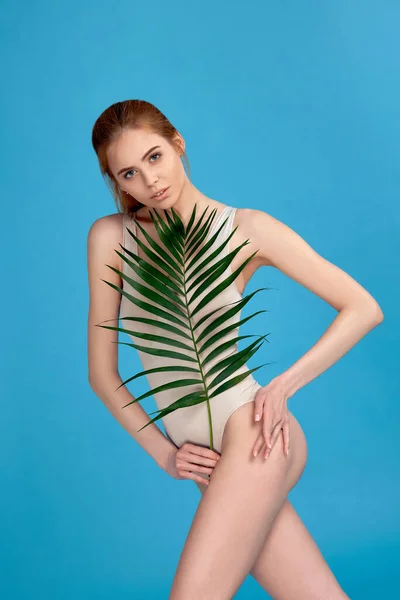 Femeie cu corp perfect în costum de corp care deține frunze de palmier — Fotografie, imagine de stoc