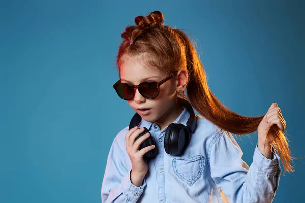 Vörös hajú lány napszemüvegben és vezeték nélküli fülhallgatóval — Stock Fotó