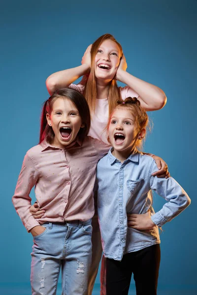 Tres niños niñas de pie juntos sobre fondo azul — Foto de Stock