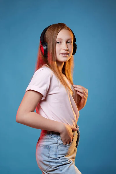 Menina adolescente bonito com cabelo vermelho em fones de ouvido sem fio — Fotografia de Stock