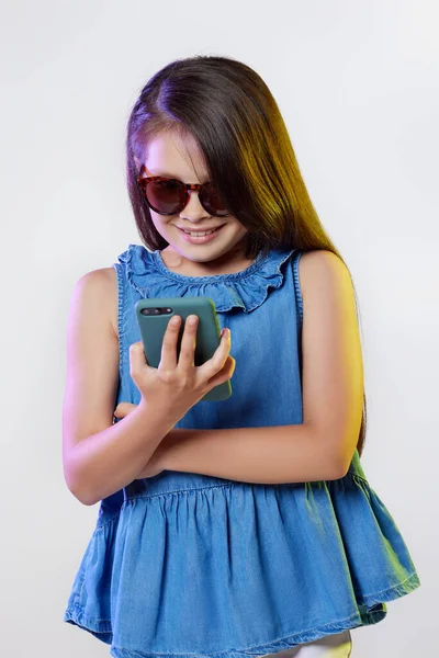 Menina em óculos de sol usando smartphone no fundo branco — Fotografia de Stock