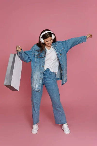 Mujer hermosa feliz en auriculares con bolsas de compras — Foto de Stock