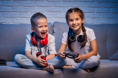 Oyun konsoluyla oyun oynayan çocuklar