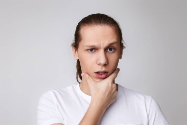 Genç yakışıklı adam çenesine dokunup düşünüyor.