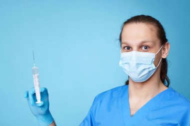 Doktor üniforması giyen bir adam elinde şırınga tutuyor.