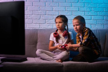 Oyun konsoluyla oyun oynayan çocuklar