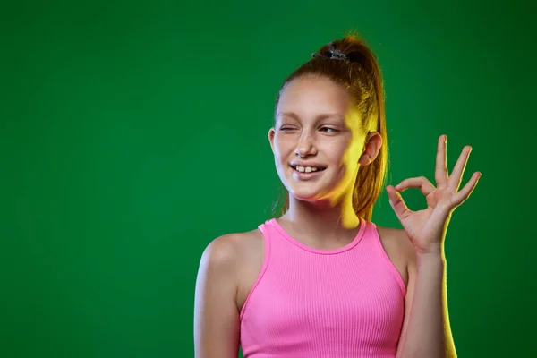 Подросток показывает ОК жест на зеленом фоне. — стоковое фото
