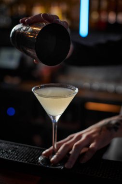 Erkek barmen elleri çelik karıştırıcıyla kokteyl yapıyor.