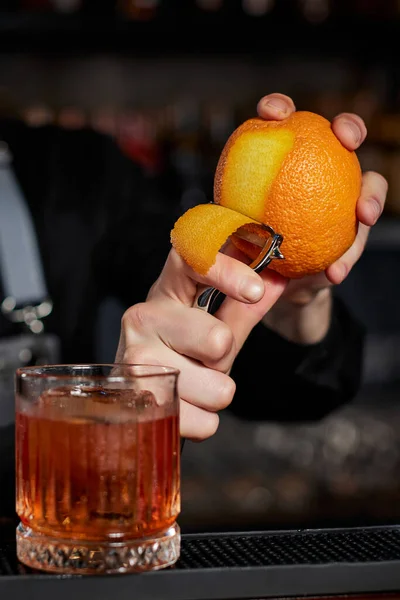 Μπάρμαν κάνει ένα κοκτέιλ σε ένα ποτήρι με φλούδα πορτοκαλιού — Φωτογραφία Αρχείου