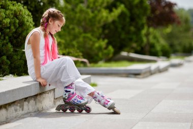 Parkta paten kayan sevimli küçük bir kız..