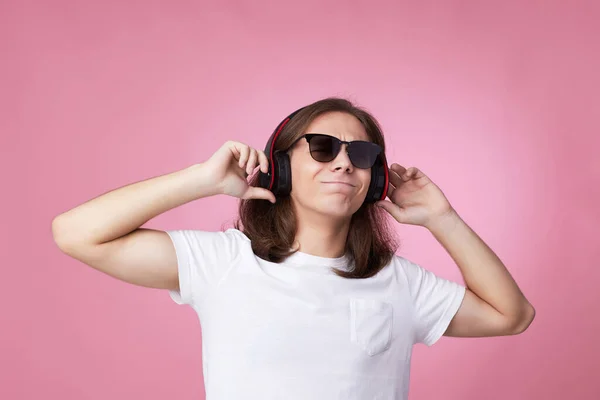 Uomo in occhiali da sole ascolta musica con cuffie e balli — Foto Stock