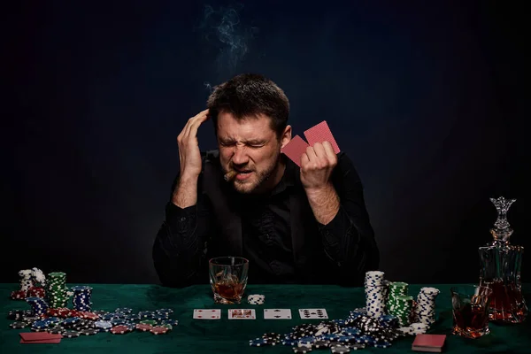 Bearded casino player man playing poker on green table