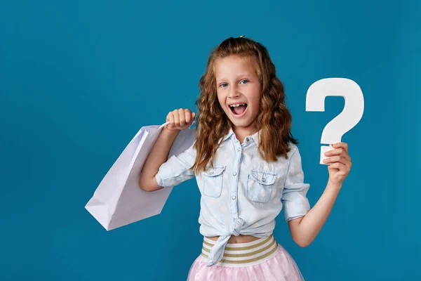 Kind hält viele Einkaufstüten und Fragezeichen in der Hand — Stockfoto