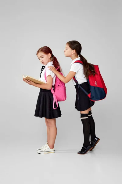 Dos amigos alegres colegialas con mochilas leer libro — Foto de Stock