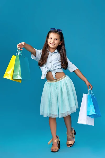 Ευτυχισμένο μικρό καυκάσιο κοριτσάκι κρατά πολλές τσάντες για ψώνια — Φωτογραφία Αρχείου