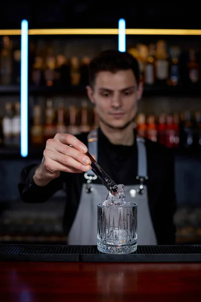 Barman coloca os cubos de gelo em um copo — Fotografia de Stock