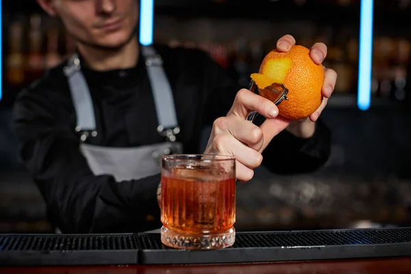 A csapos narancshéjas pohárban készít koktélt. — Stock Fotó