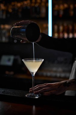 Erkek barmen elleri çelik karıştırıcıyla kokteyl yapıyor.