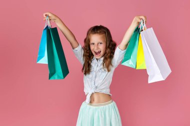 Küçük beyaz kız alışveriş torbaları tutuyor.