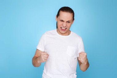 Tişörtlü genç adam boks jestiyle ayakta duruyor.