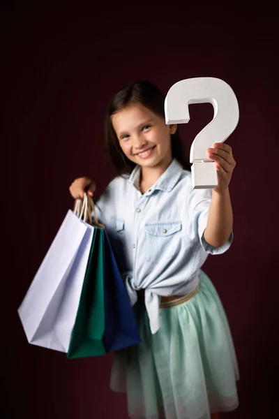어린 소녀가 쇼핑백 과 물음표를 많이 들고 있다 — 스톡 사진