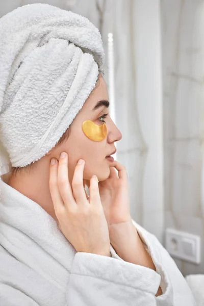 Hermosa mujer con parches para los ojos en albornoces blancos en el baño — Foto de Stock