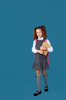 Sırt çantası ve kitap boyu uzun sevimli bir kız öğrenci..