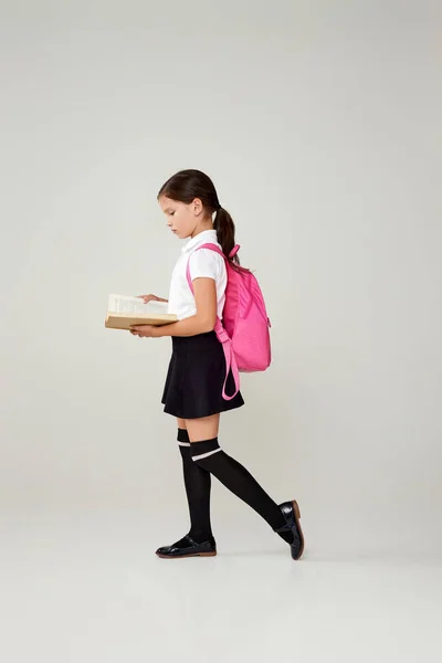 Schattig schoolmeisje met rugzak en boek volledige lengte. — Stockfoto