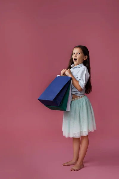 행복 한 어린 소녀가 쇼핑백을 많이 들고 있다 — 스톡 사진