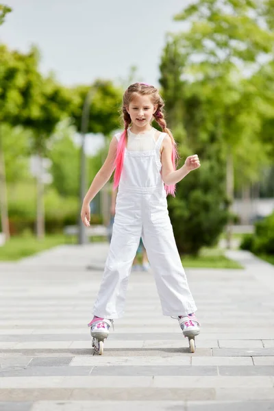 Cheerful little girl on roller skates with braided hair style — Stock Photo, Image