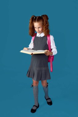 Sırt çantası ve kitap boyu uzun sevimli bir kız öğrenci..