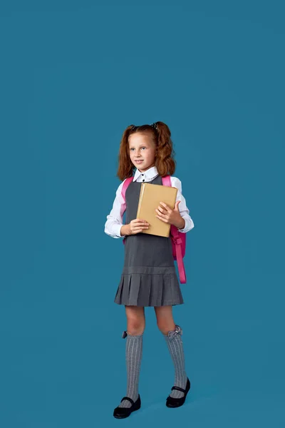 Симпатичная школьница с рюкзаком и книгой в полный рост. — стоковое фото