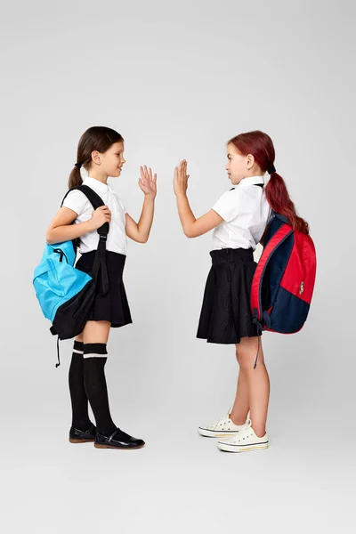 Twee gelukkig weinig vrolijk vrienden schoolmeisjes met rugzakken — Stockfoto