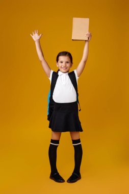 Sırt çantası ve kitap boyu uzun sevimli bir kız öğrenci..