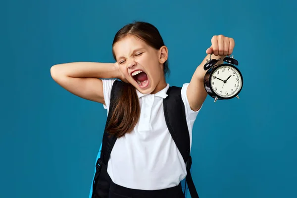 Schoolmeisje met rugzak is met wekker — Stockfoto