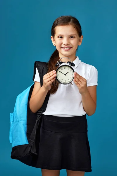 가방을 든 여학생 이 자명종 시계를 들고 있다 — 스톡 사진