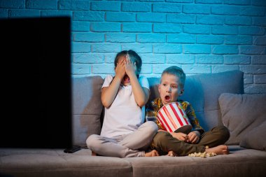 Uzaktan kumandalı iki çocuk televizyon izliyor.
